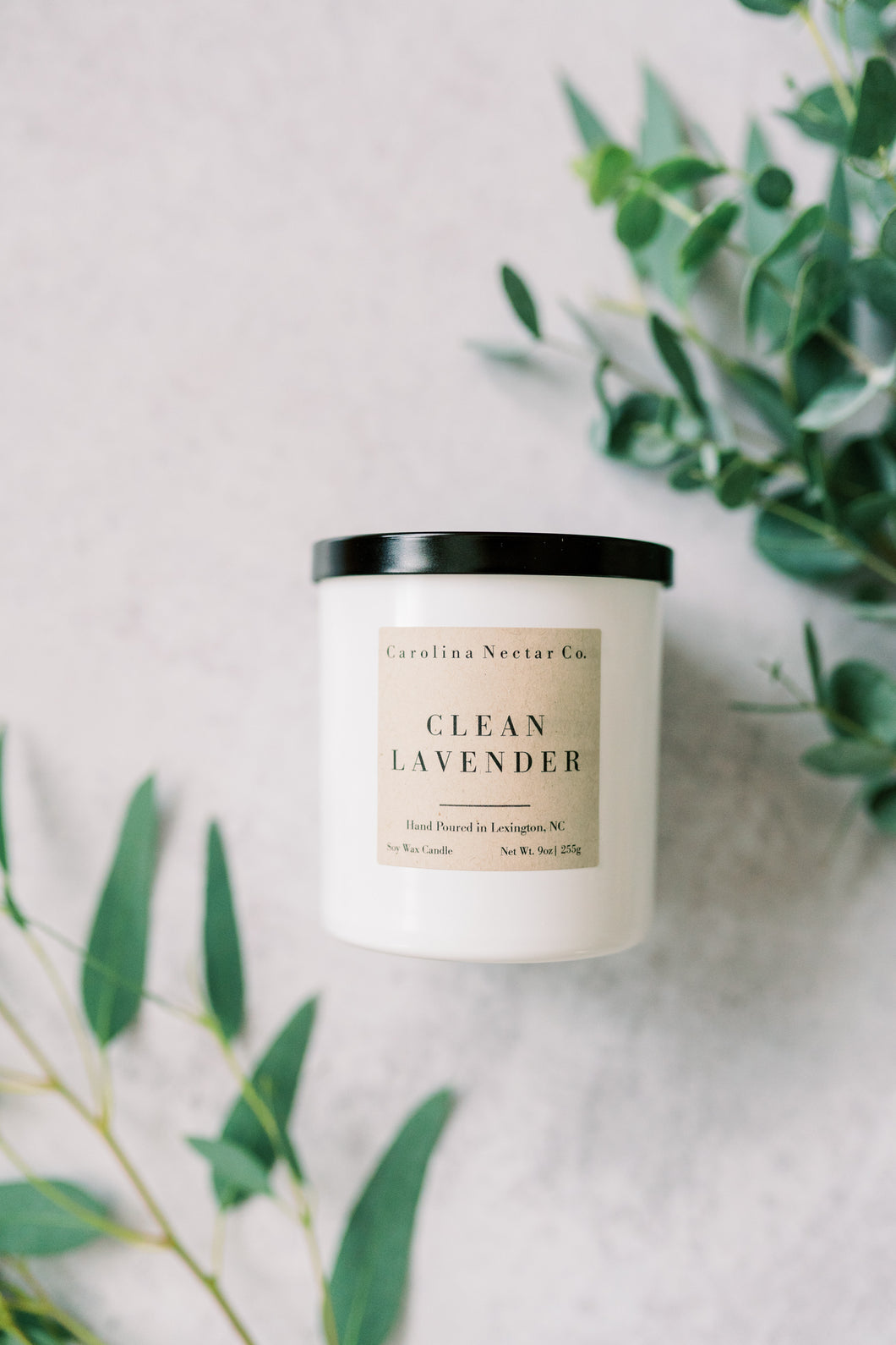 clean lavender soy candle in white glass jar with black metal top